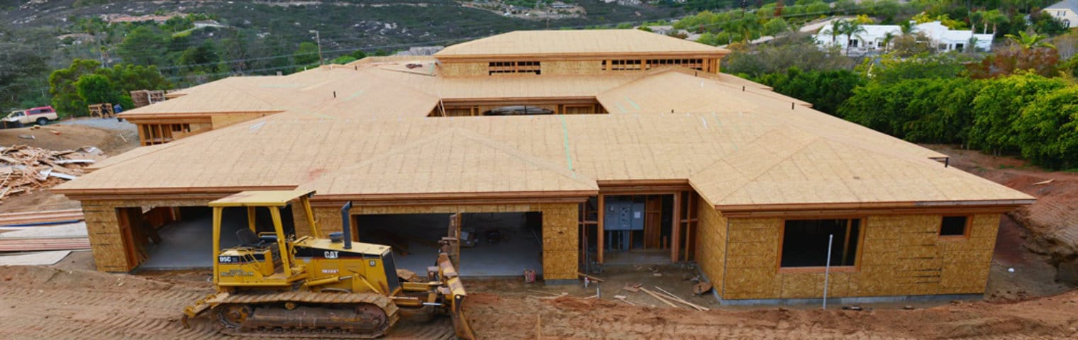 A house under construction with a bulldozer in front of it